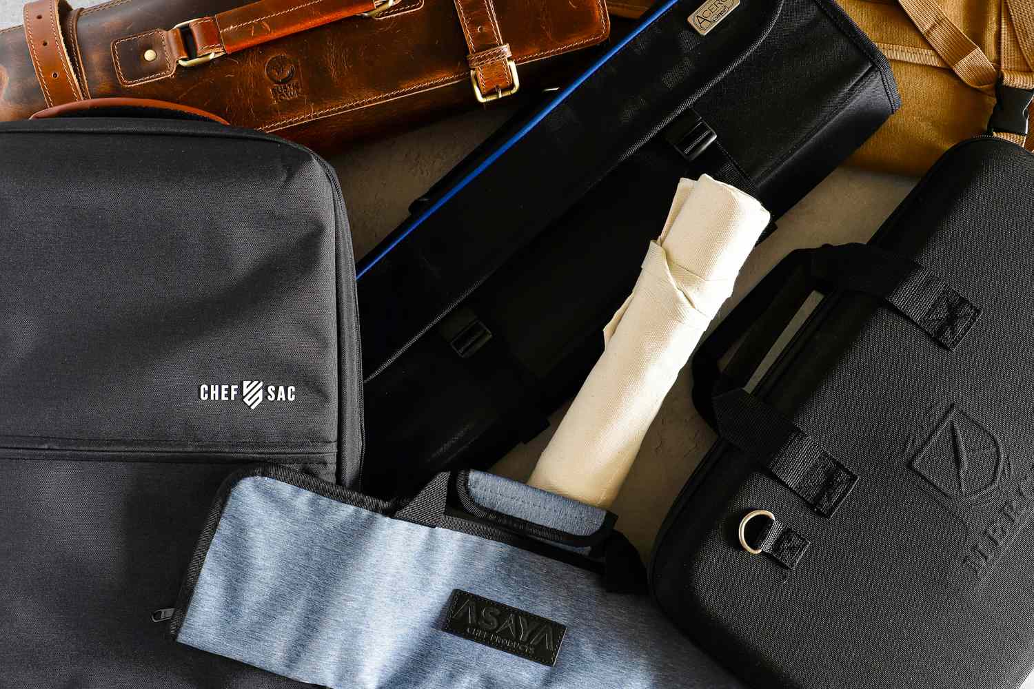 A variety of knife rolls and bags arranged showing branding from different companies