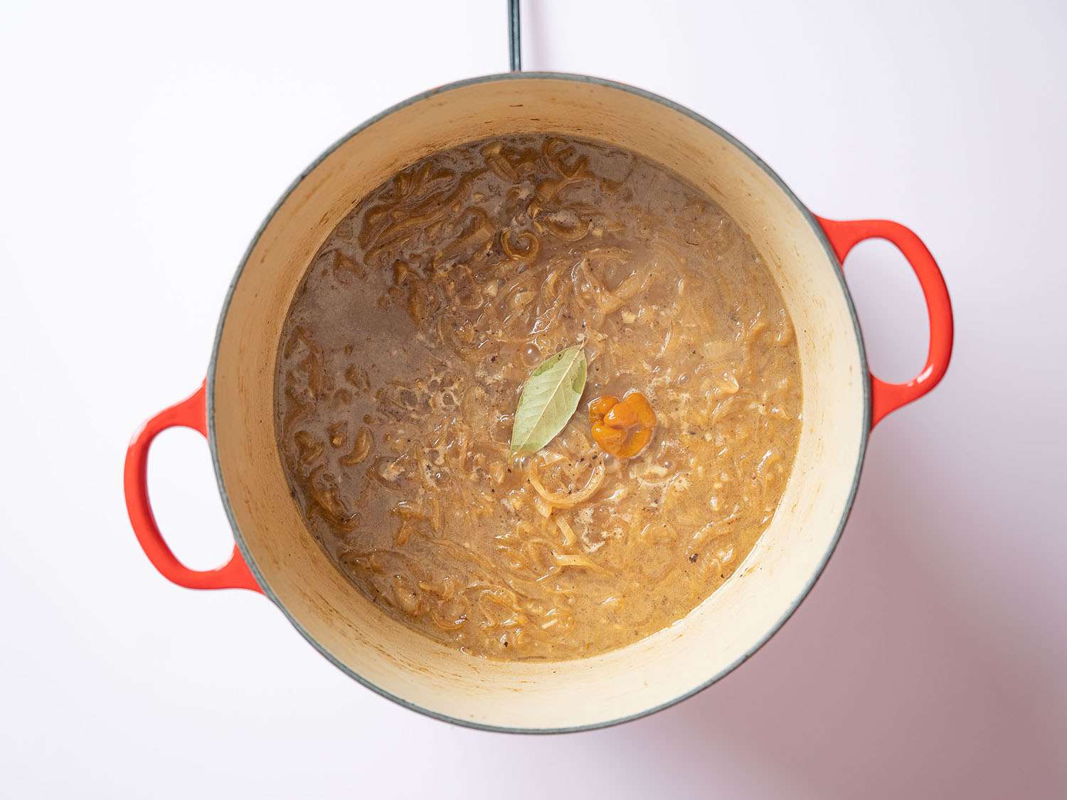 Chicken stock, Scotch bonnet pepper, bay leaf, and chicken boiling.