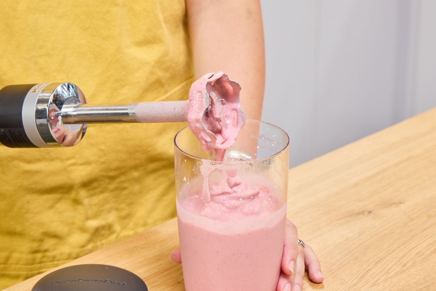 A person uses the KitchenAid Go Cordless Hand Blender to make a smoothie