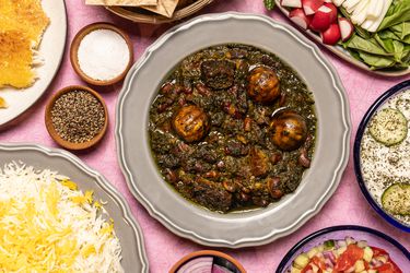 Overhead of Khoresh E Ghormeh Sabzi surrounded with rice, dips, and vegetables 