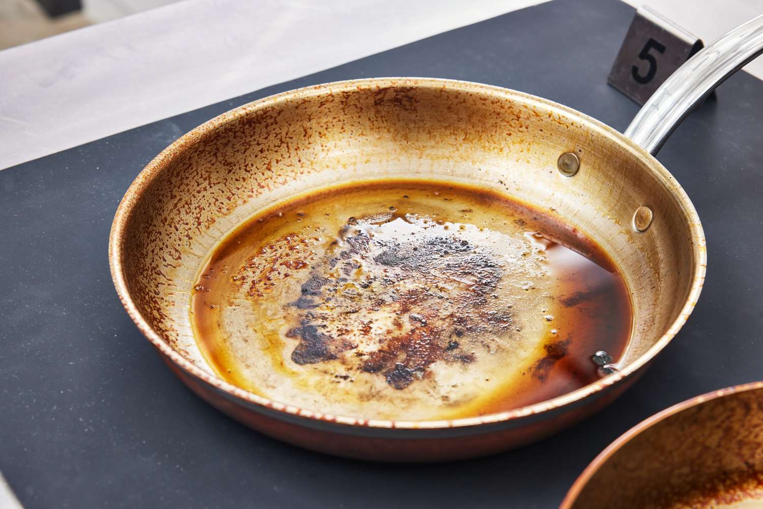 A pan with leftover cooking residue and liquid on a dark background