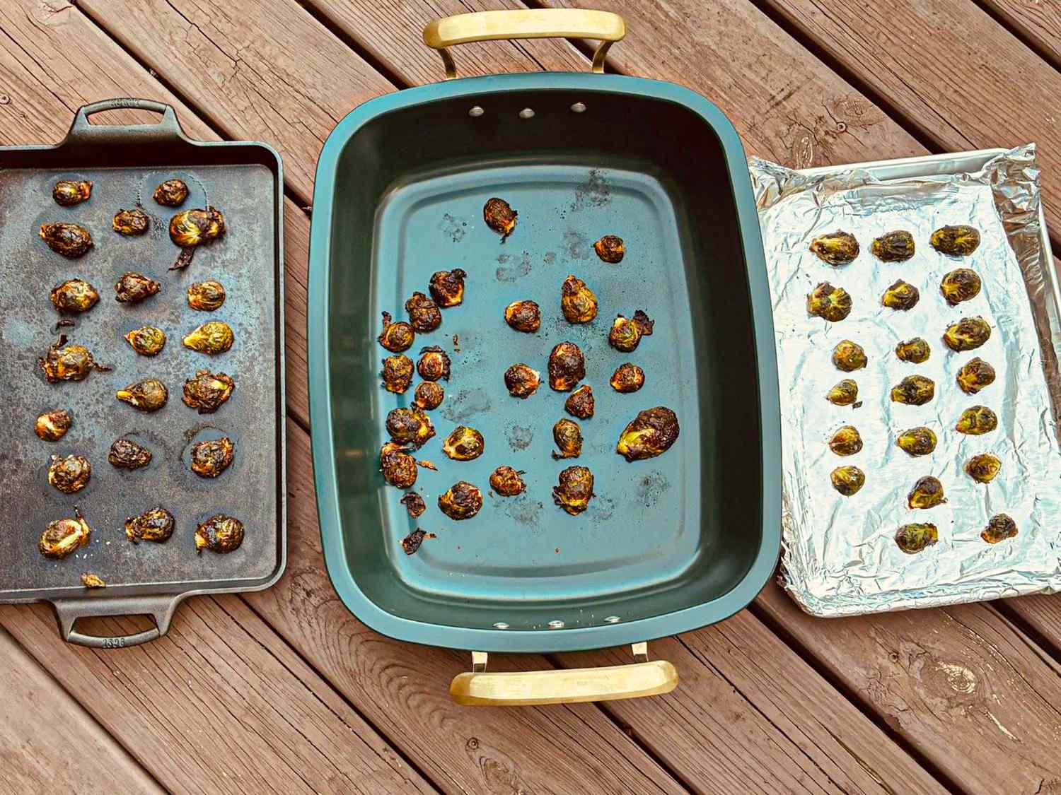 Three pans with roasted vegetables arranged on a wooden surface