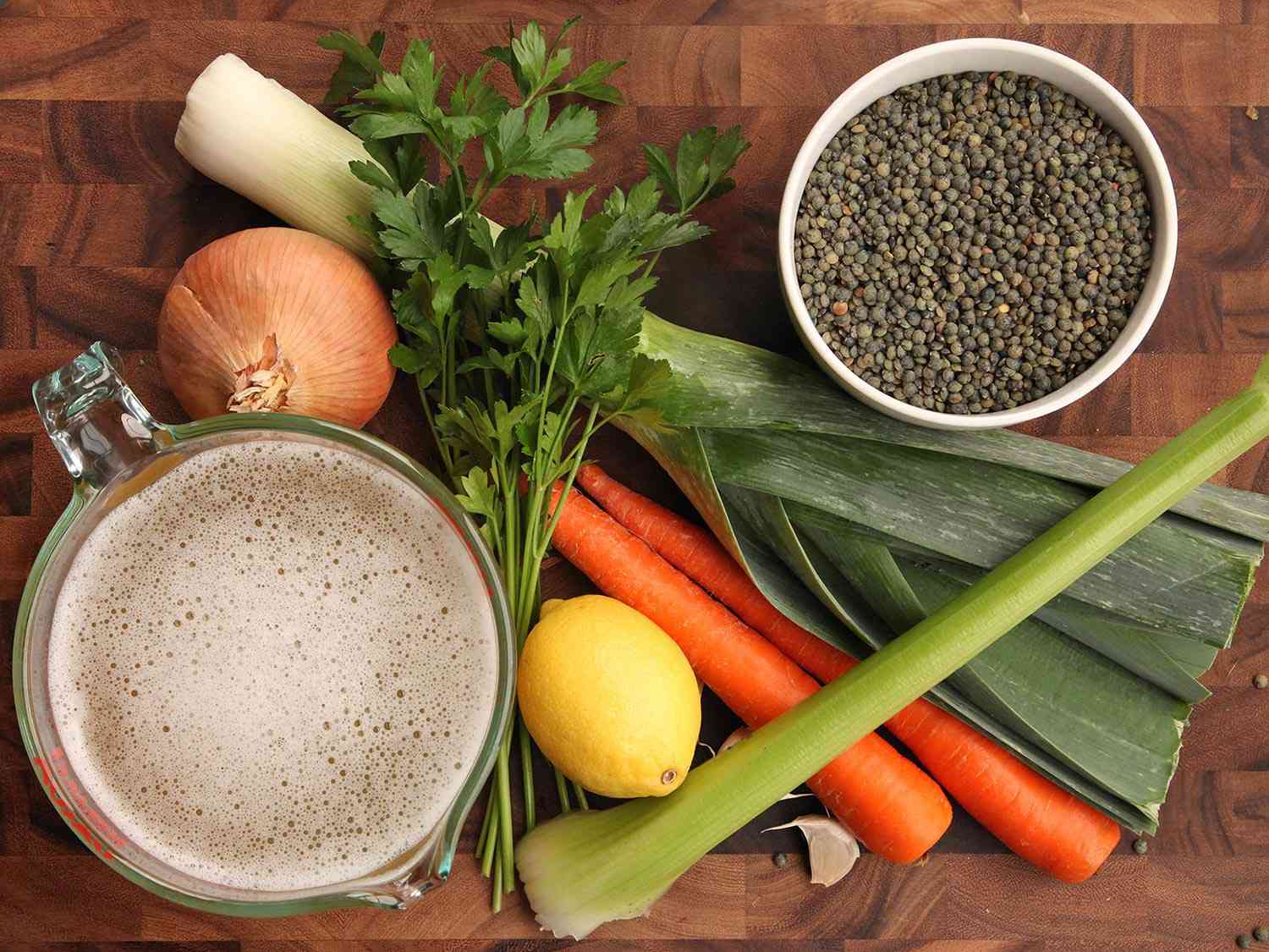 All the ingredients for lentil soup with gremolata: lentils, leek, parsley, carrot, onion, celery, garlic, and stock.