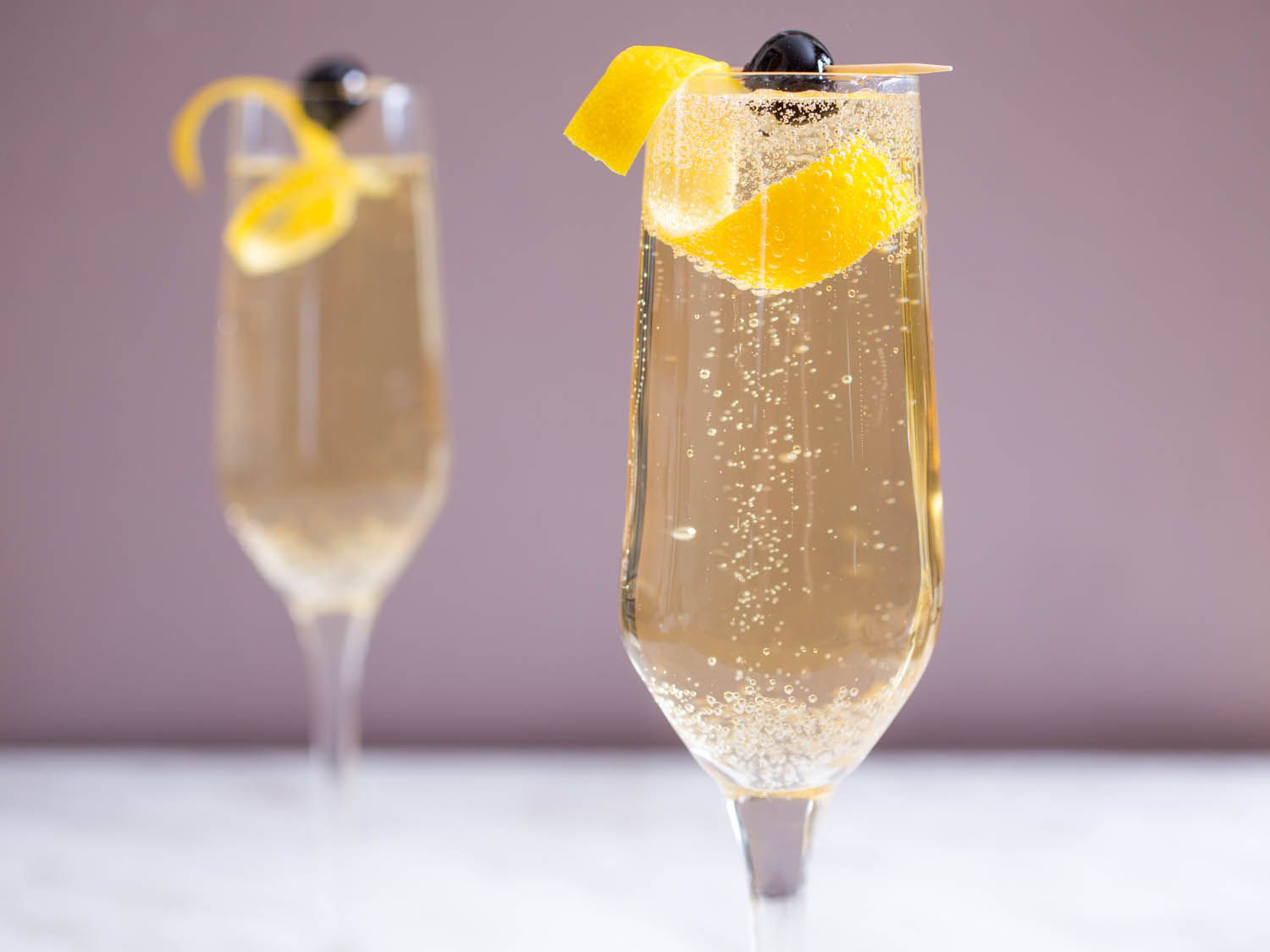 French 75's served in Champagne flutes with a lemon twist and skewered maraschino cherry garnish.