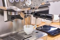 A person brews espresso in the Breville The Barista Express Espresso Machine