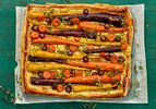 carrot tart on a sheet of parchment paper on a green wooden surface 