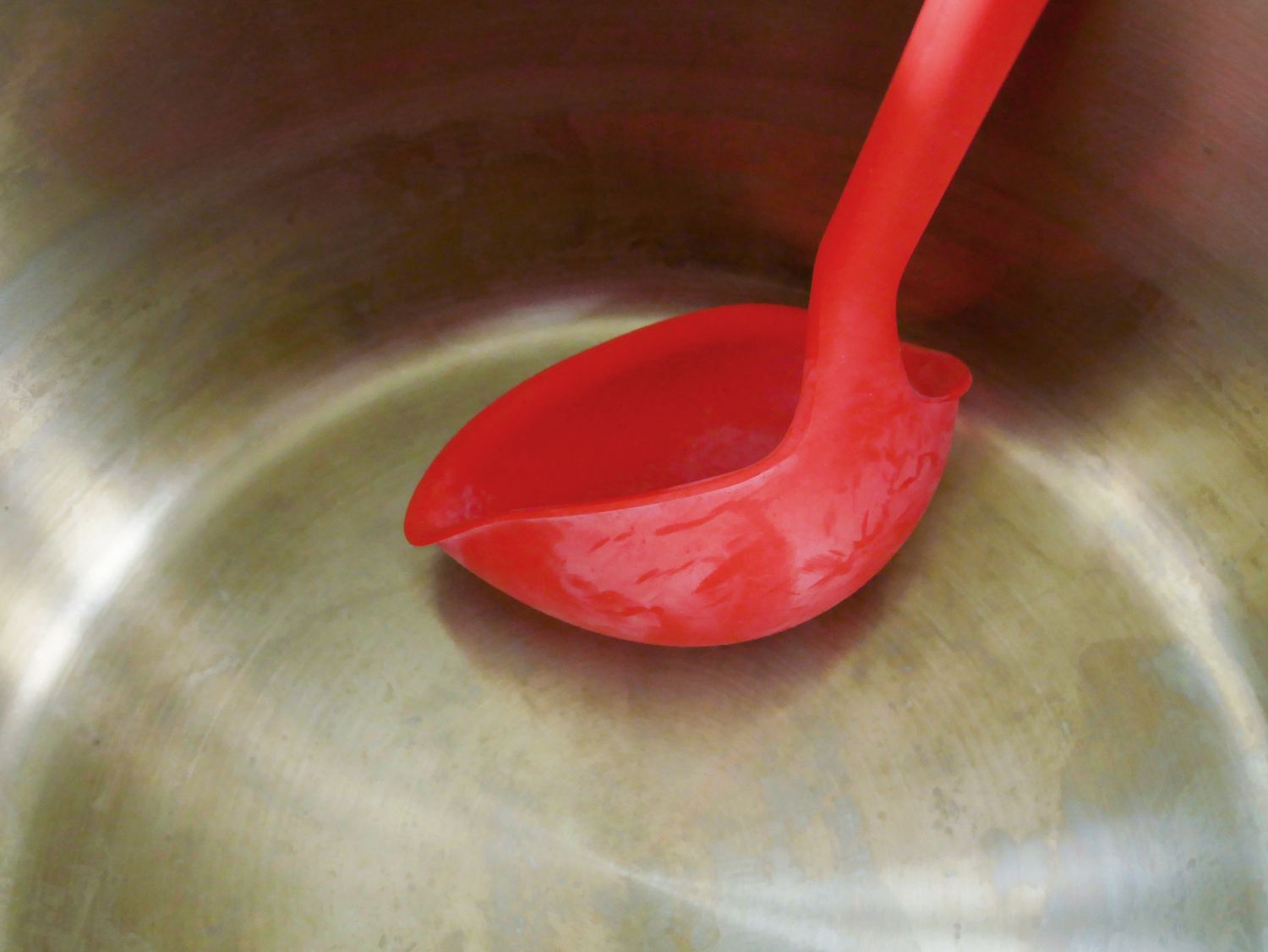 the gir ladle pressed into the bottom of a stock pot to show how malleable it is