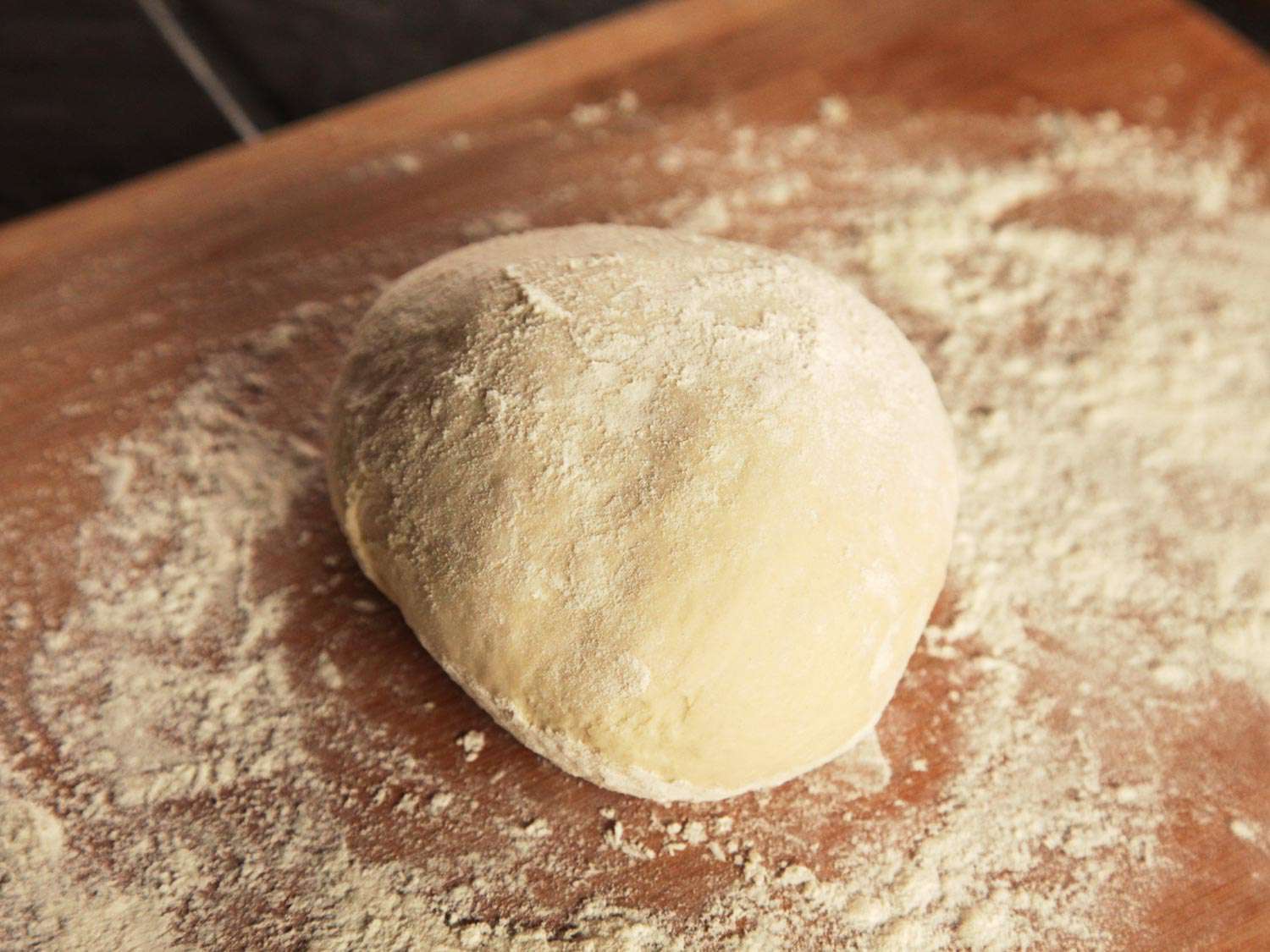 A ball of dough for pull-apart garlic knots, on a flour-dusted wooden surface