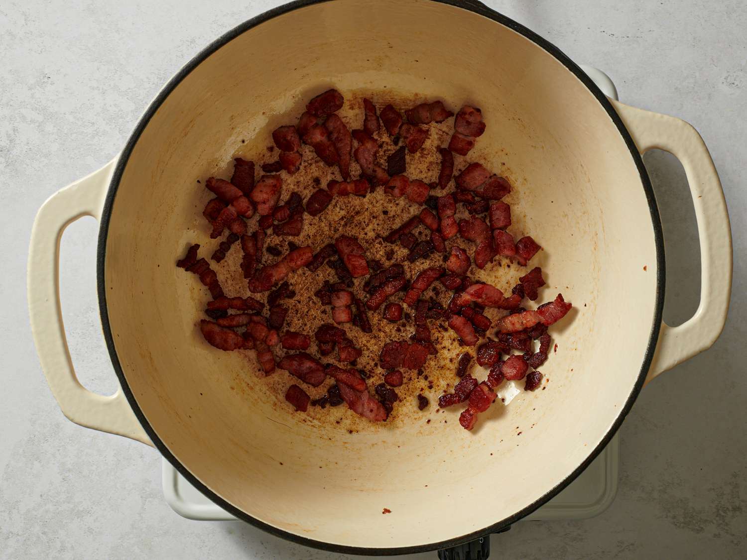 Browned bacon with rendered fat inside a large Dutch oven.