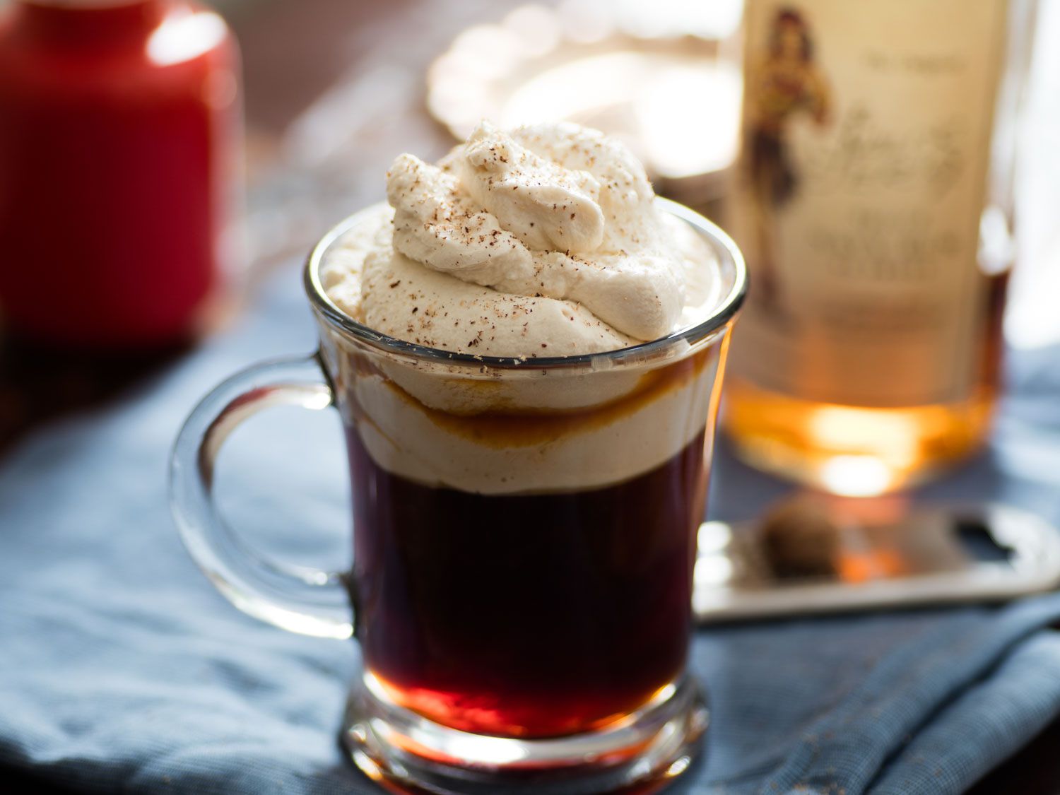 A glass mug filled with Spiced-Rum Coffee and topped with a generous mound of butterscotch whipped cream.
