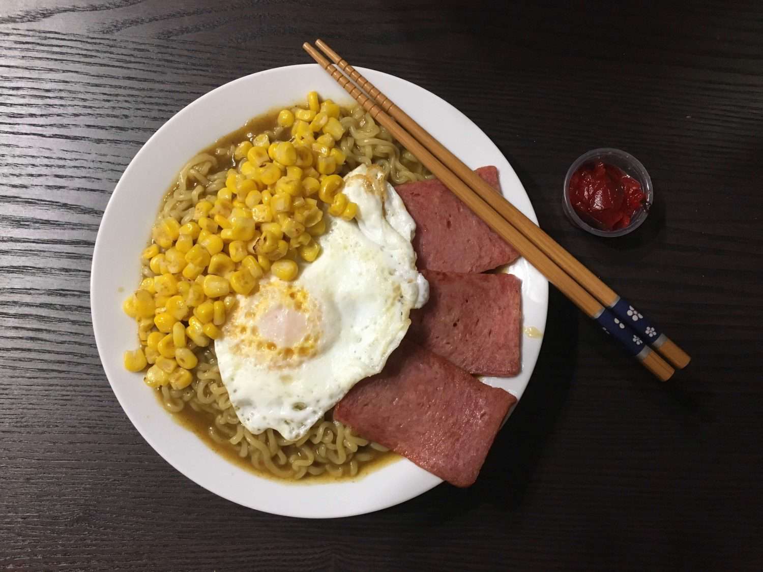 Overhead view of a bowl of curry-men with a fried egg and spam slices