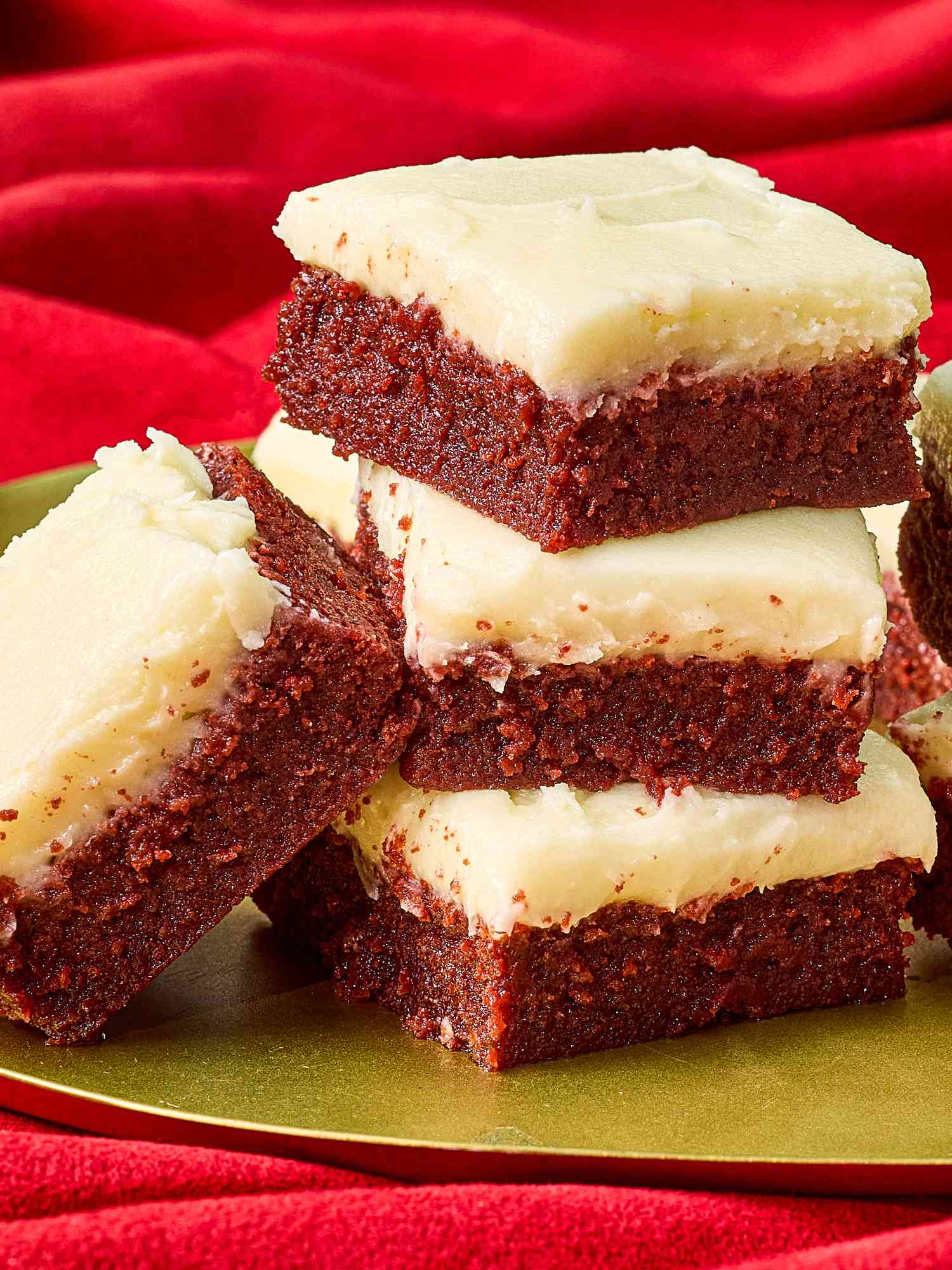 red velvet brownie squares stacked together on a gold platter on top of a red velvet backdrop