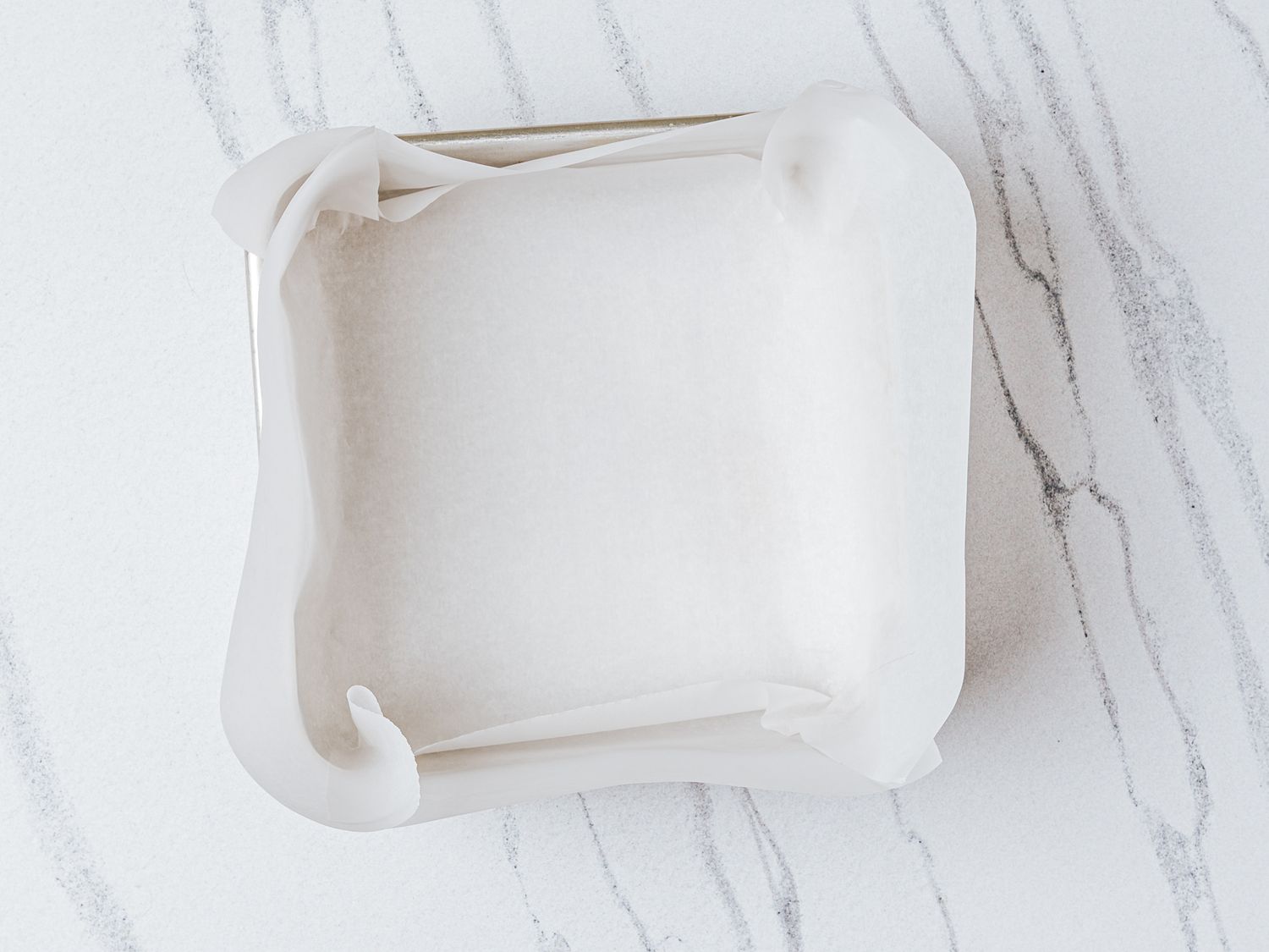 A square baking pan lined with parchment paper