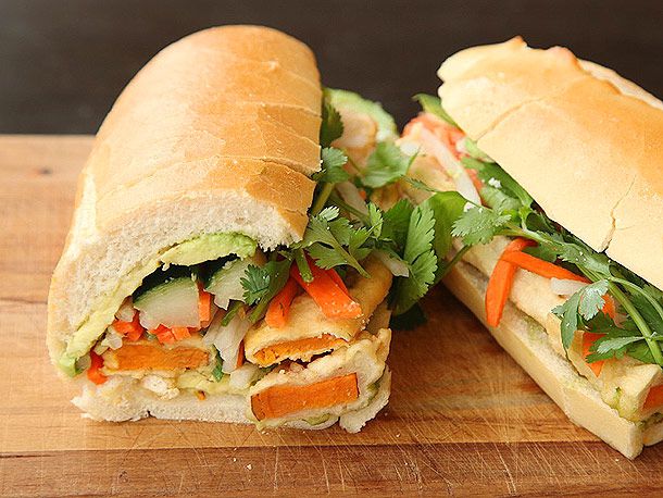 A cross-section view of sweet potato bánh mì layered with avocado, cucumber, pickled daikon and carrot, and fresh cilantro.