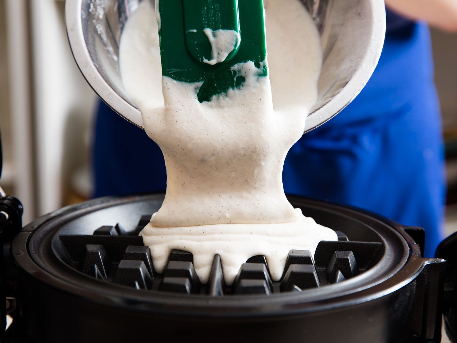 Transferring waffle batter to a waffle iron. 