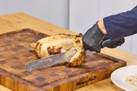 A person cuts chicken using the Victorinox Fibrox Pro 12-Inch Slicing Knife with Granton Blade
