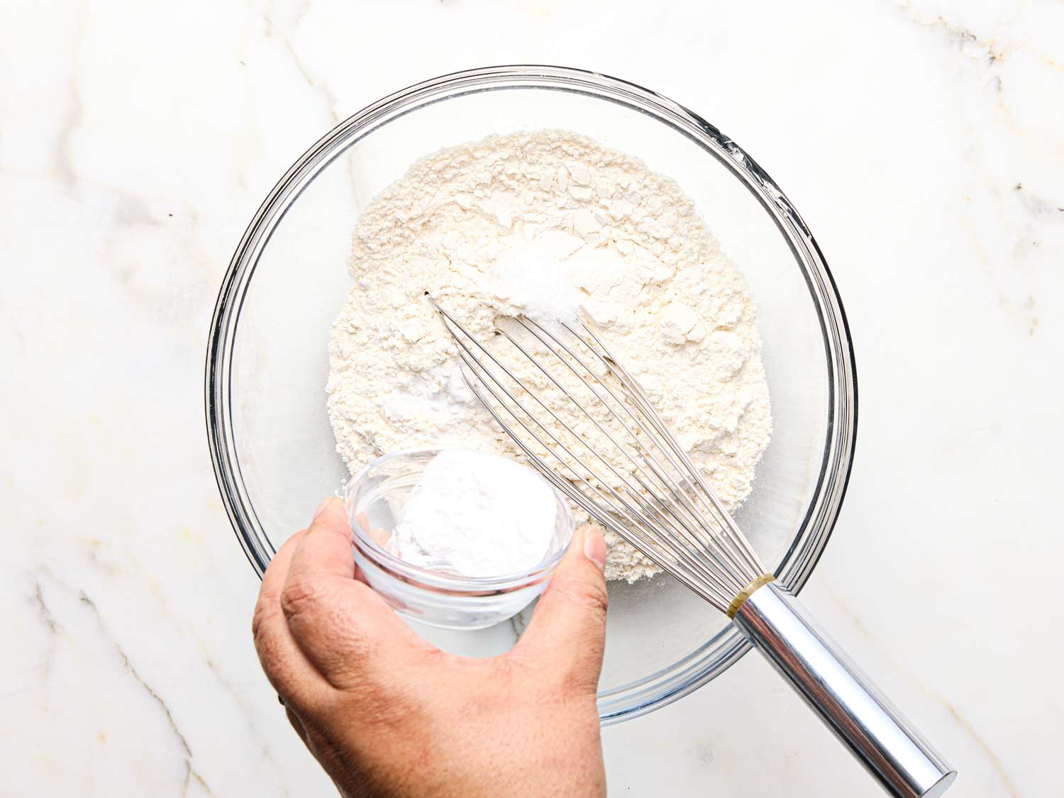 Mixing dry ingredients with a whisk in a clear bowl