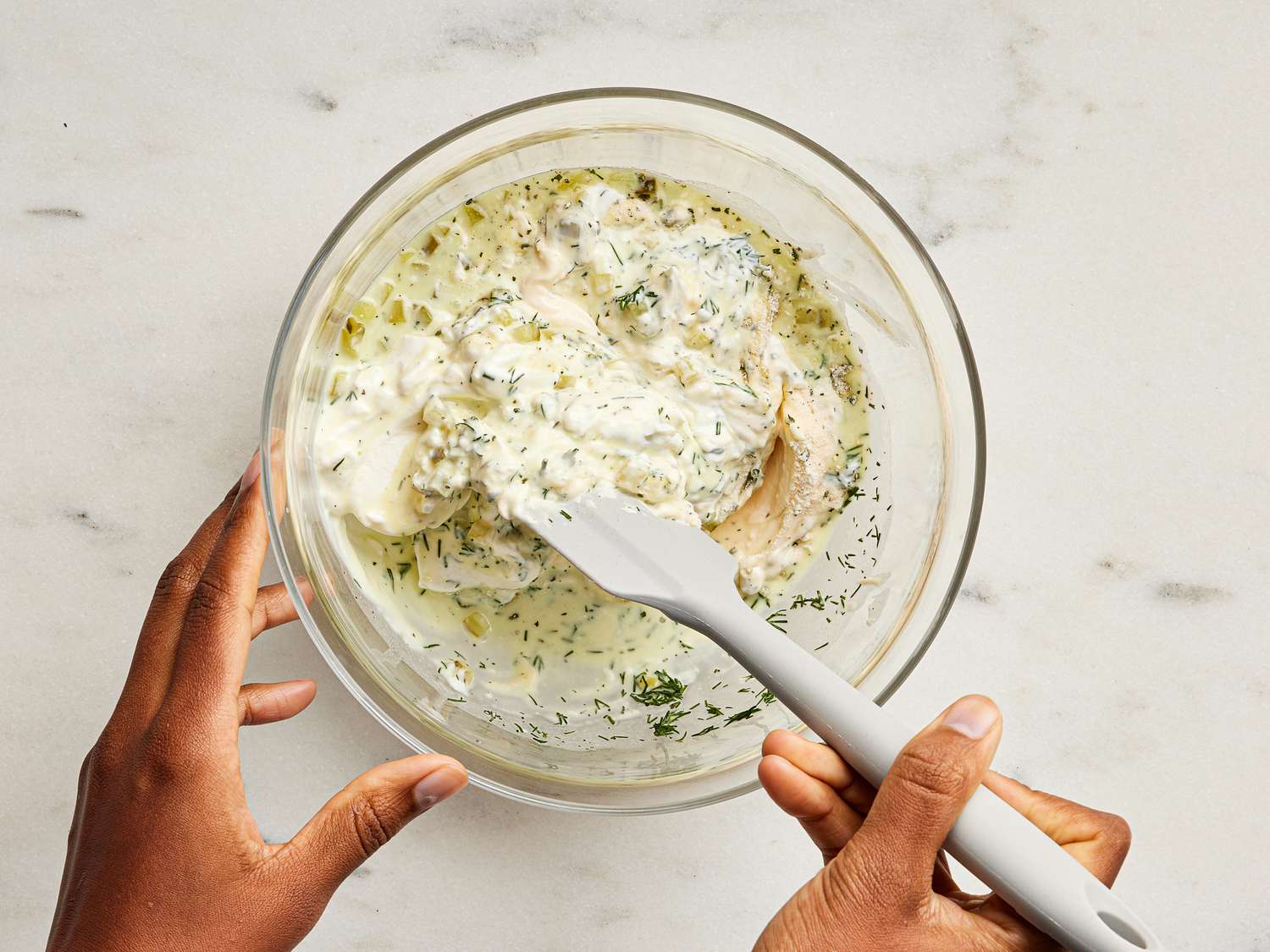 sour cream, mayonnaise, ranch dressing, pickles, pickle juice and dill being mixed together in a glass bowl 