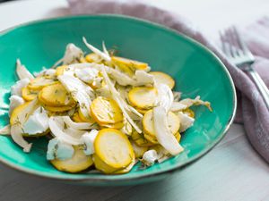 Summer squash salad with goat cheese, fennel, and dill, served in a shallow turquoise bowl.