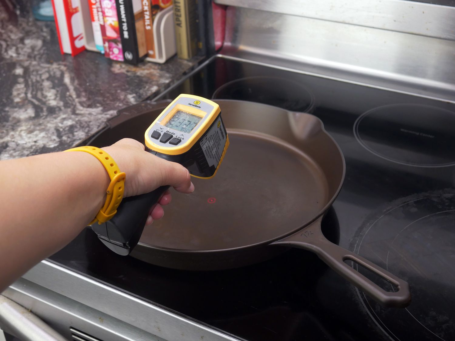 a person taking the temperature of the skillet's surface using an infrared thermometer
