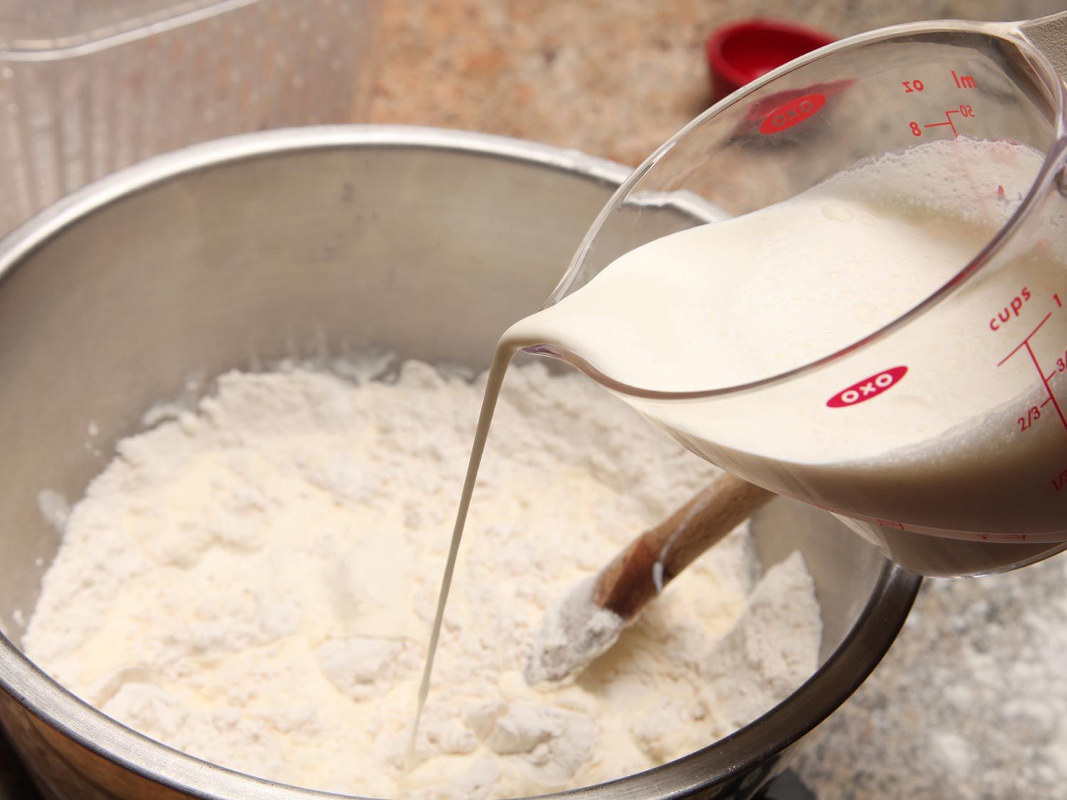 Pouring cream into a bowl of flour for two-ingredient biscuits.