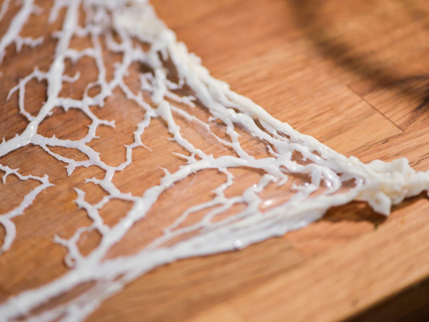 A sheet of caul fat is unrolled and stretched out on a work surface.