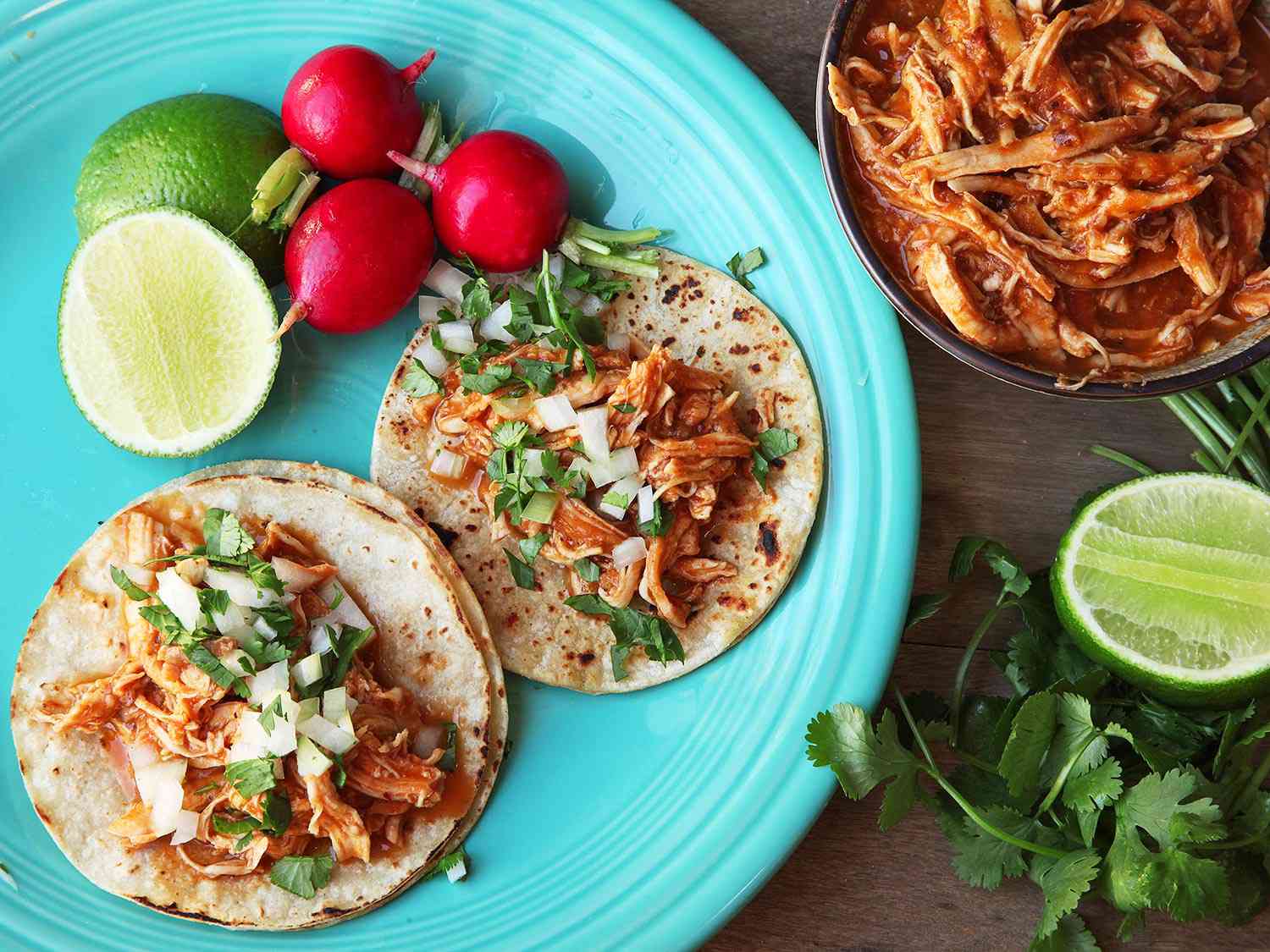Chicken tinga made into two tacos served with lime and radishes