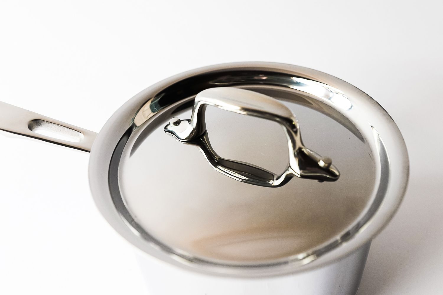 A metal saucepan with a lid and handle on a white background