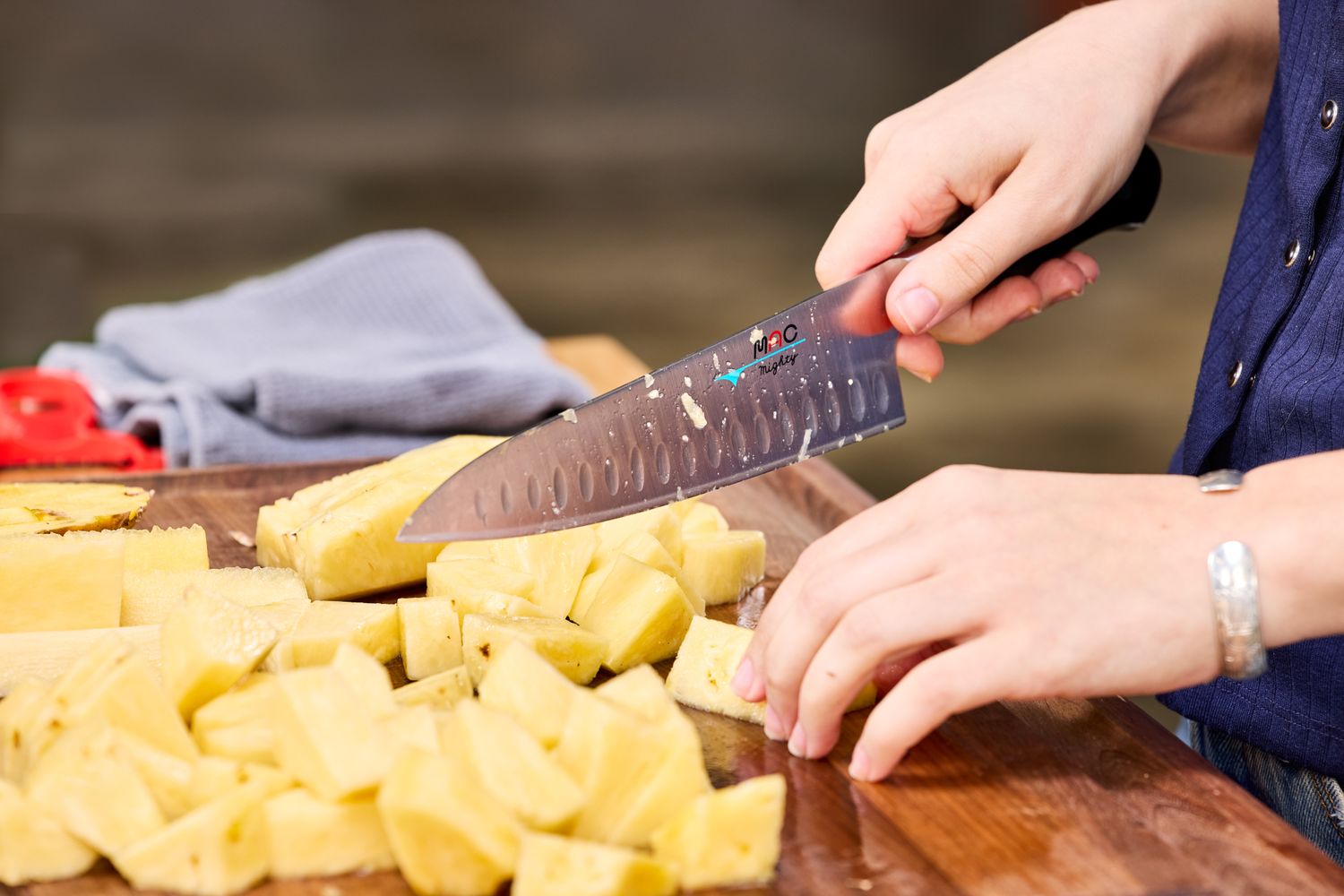 A person uses the MAC Professional 8 Inch Hollow Edge Chef's Knife to cube pineapple