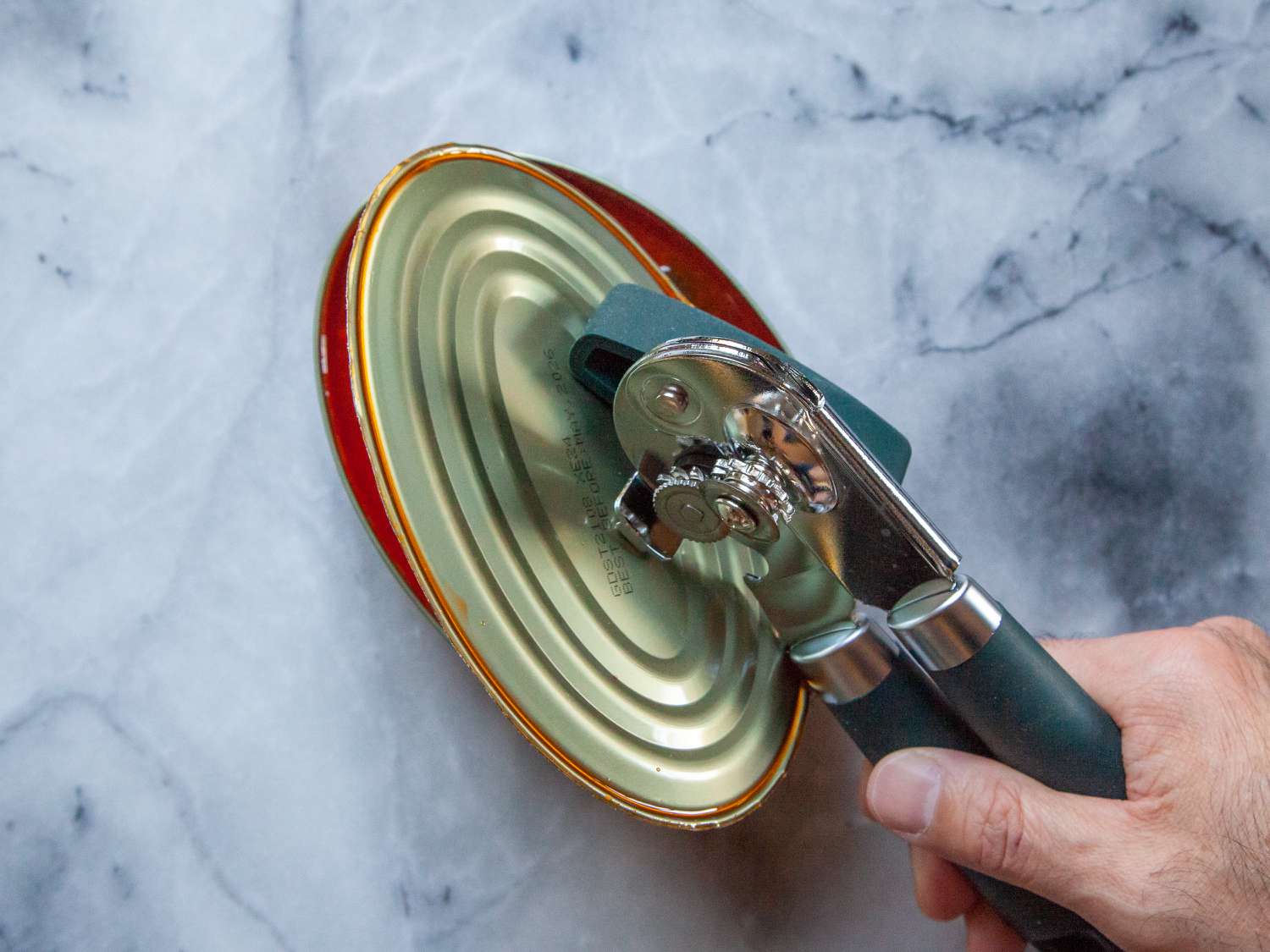Person using Beneno Can Opener on can lid 