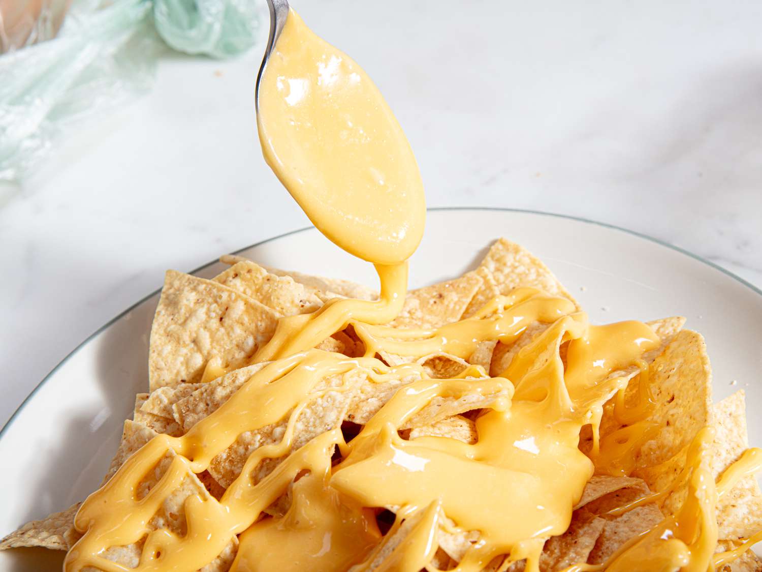 Drippy nacho cheese sauce drizzled over tortilla chips.