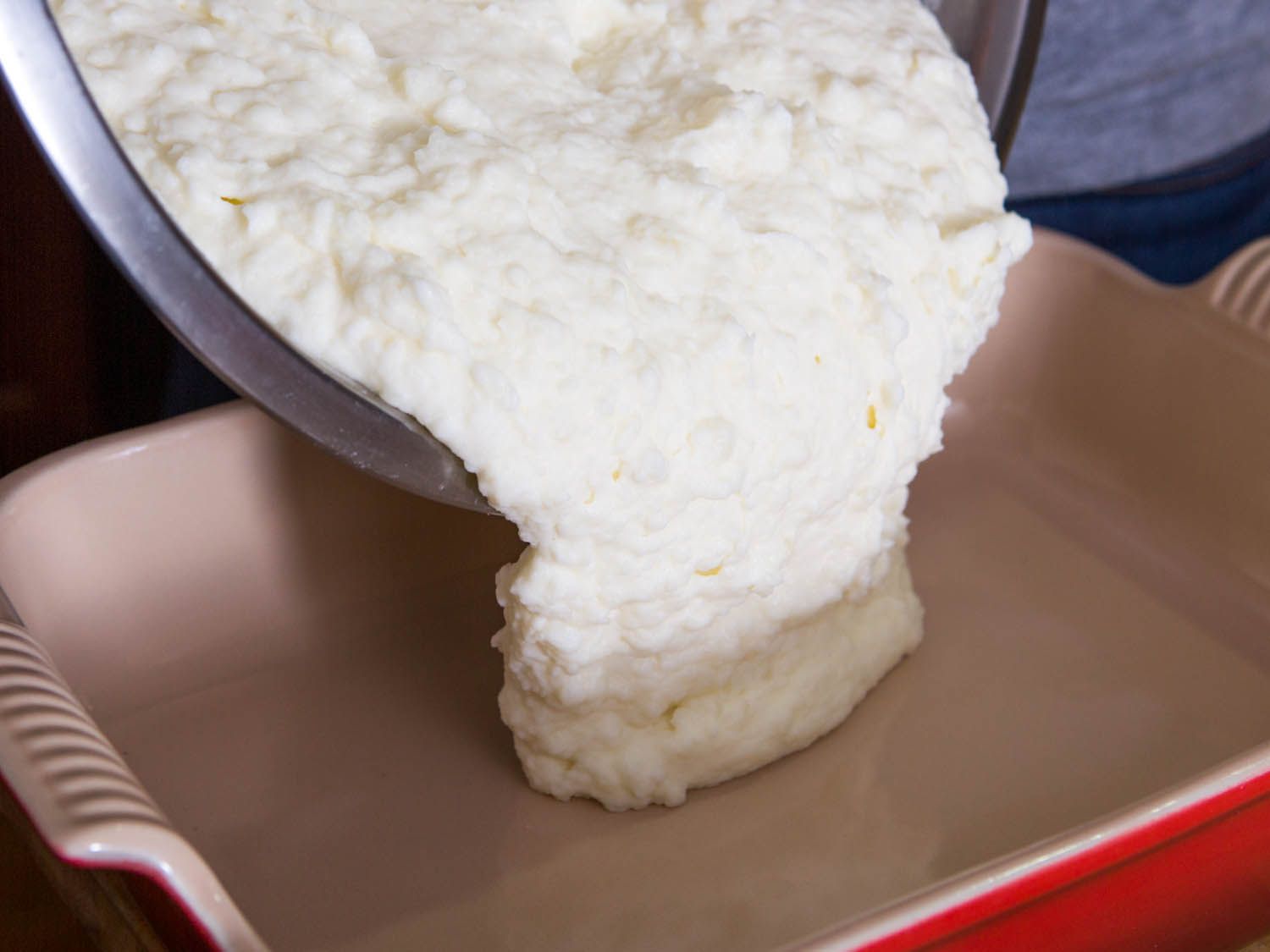Transferring masked potatoes into baking dish.