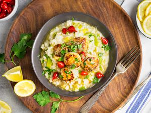 Overhead view of a dark gray bowl containing seared sea scallops with leek risotto and lemon-brown butter sauce.