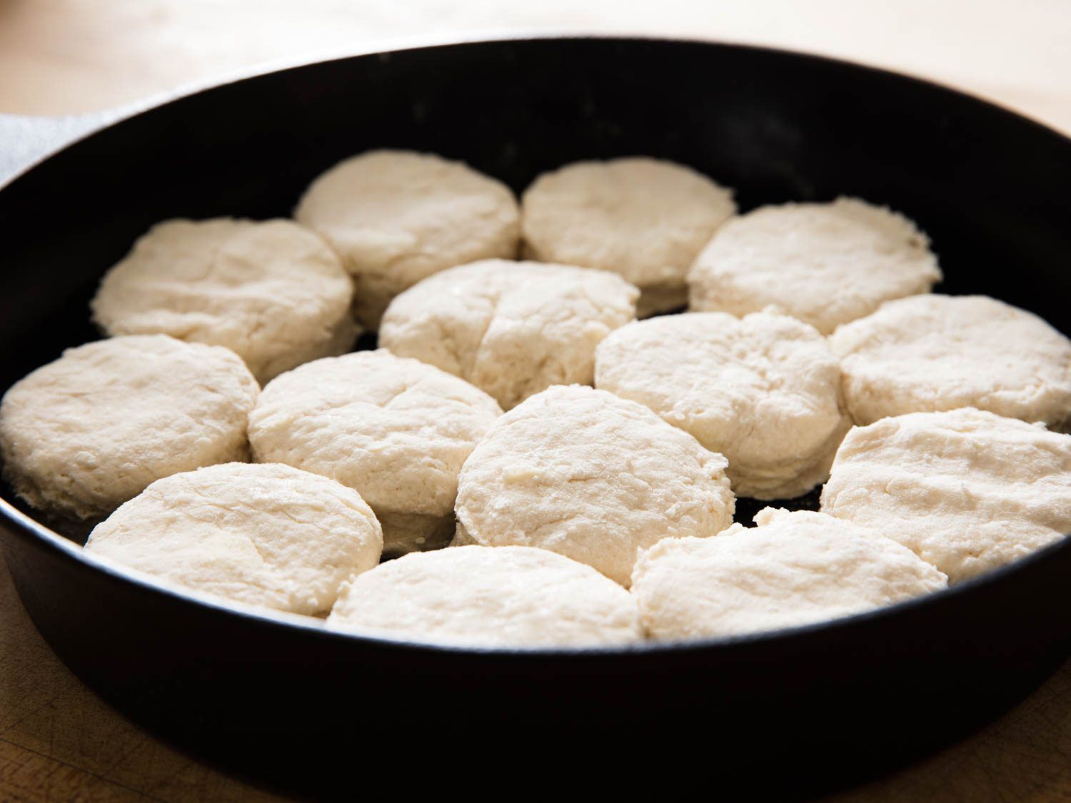 Cut rounds of yogurt biscuit dough arranged inside a cast-iron skillet.
