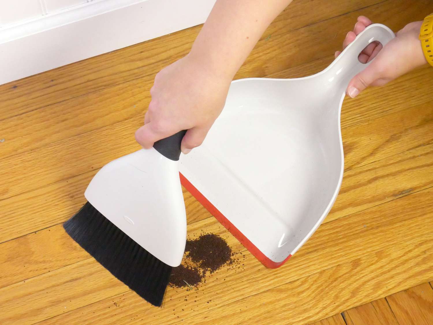 a person sweeping coffee grounds into a dustpan