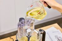 A person pours oil into the KitchenAid 13-Cup Food Processor