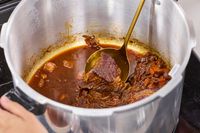 Meat cooked in the Presto 16-Quart Pressure Canner and Cooker is stirred with a ladle