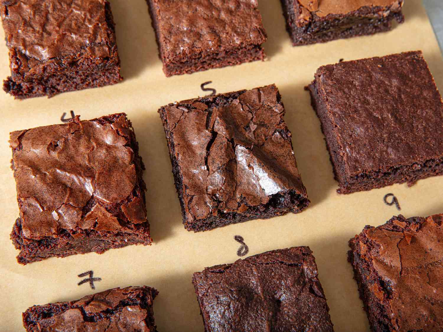 Different varieties of brownie squared lined up and numbered on parchment paper