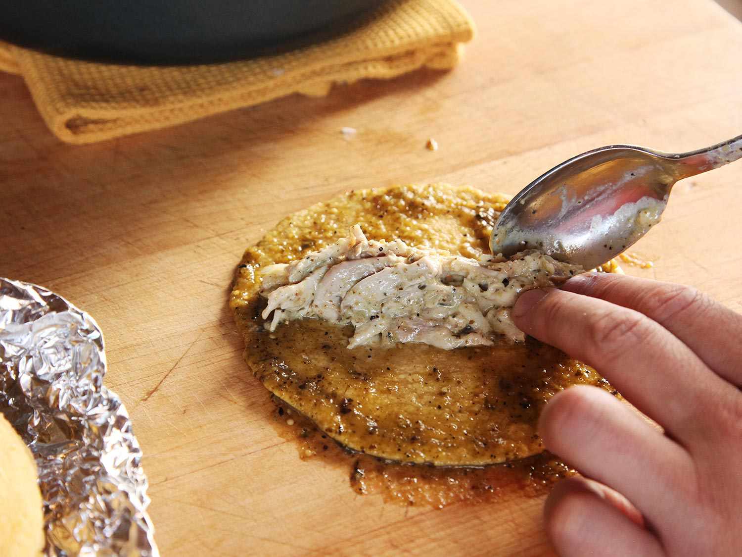 The chicken filling is spooned onto sauce-coated tortillas.