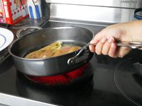a person swirling oil with chicken cutlets in a saute pan