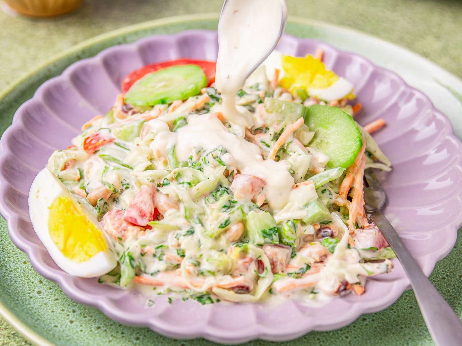 Nigerian salad served in a plate with a creamy dressing being poured on top