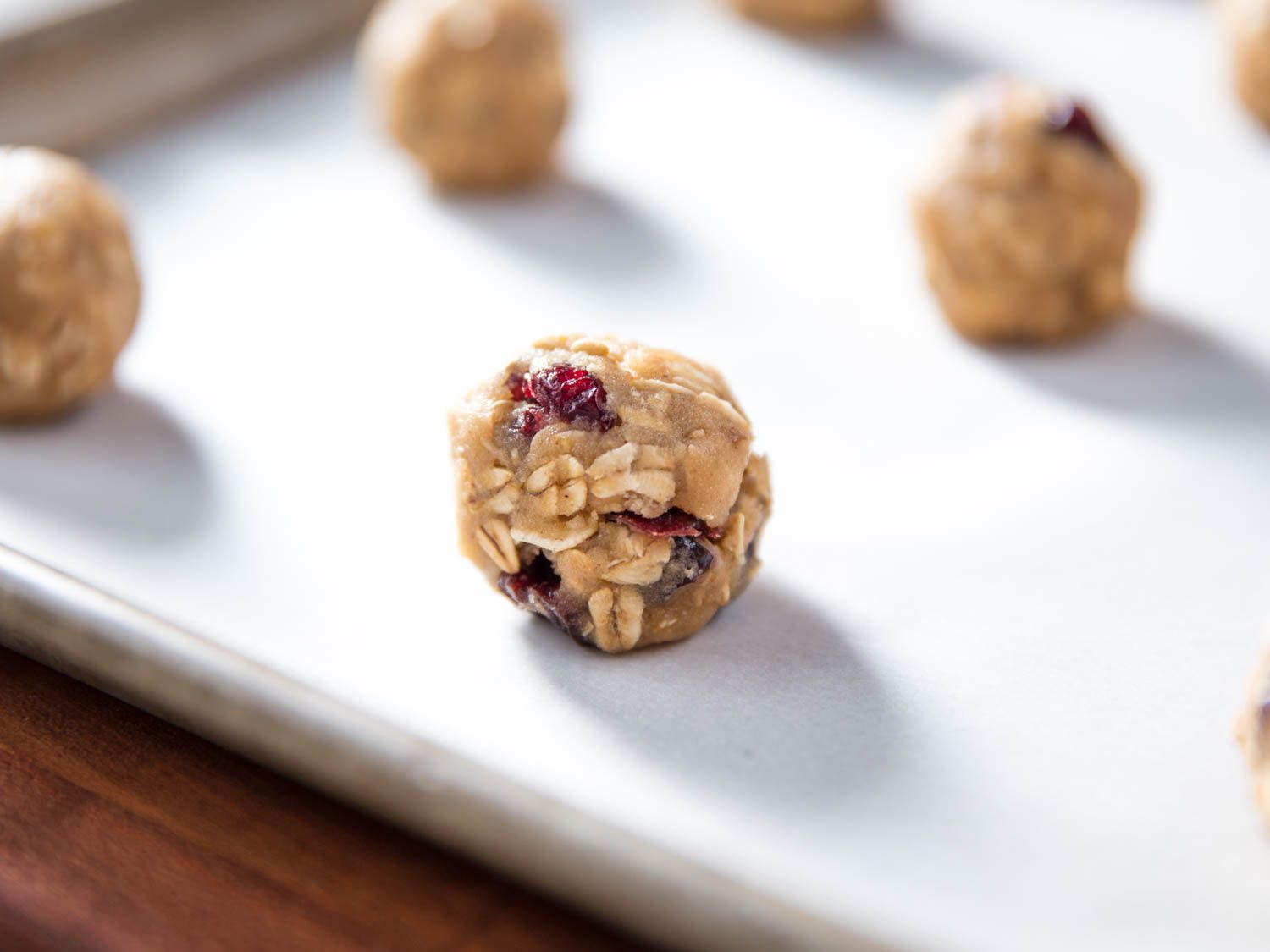 Portioned oatmeal cookie dough on a baking sheet lined with parchment paper. 