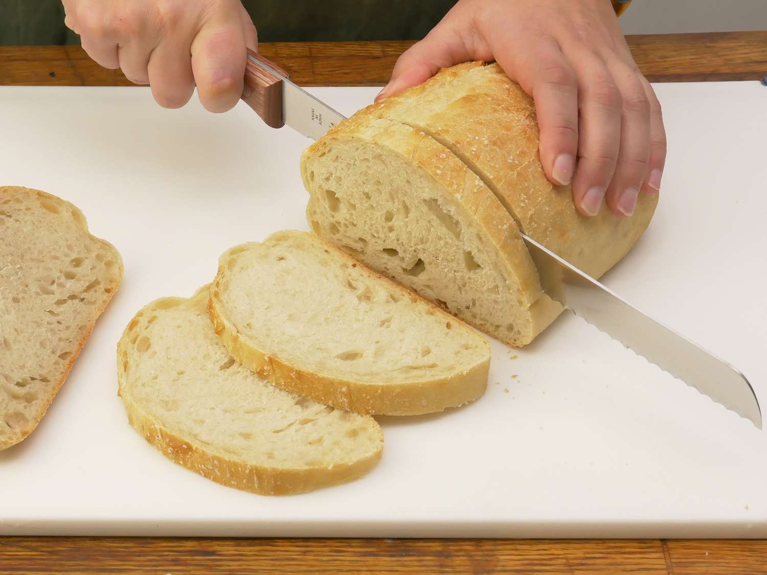 a person slicing bread on the winco cutting board