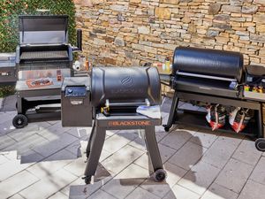 Three pellet grills on an outdoor patio.
