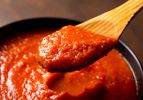 A wooden spoon scooping out a portion of quick and easy Italian-American red sauce that tastes like you spent all day making tomato sauce.