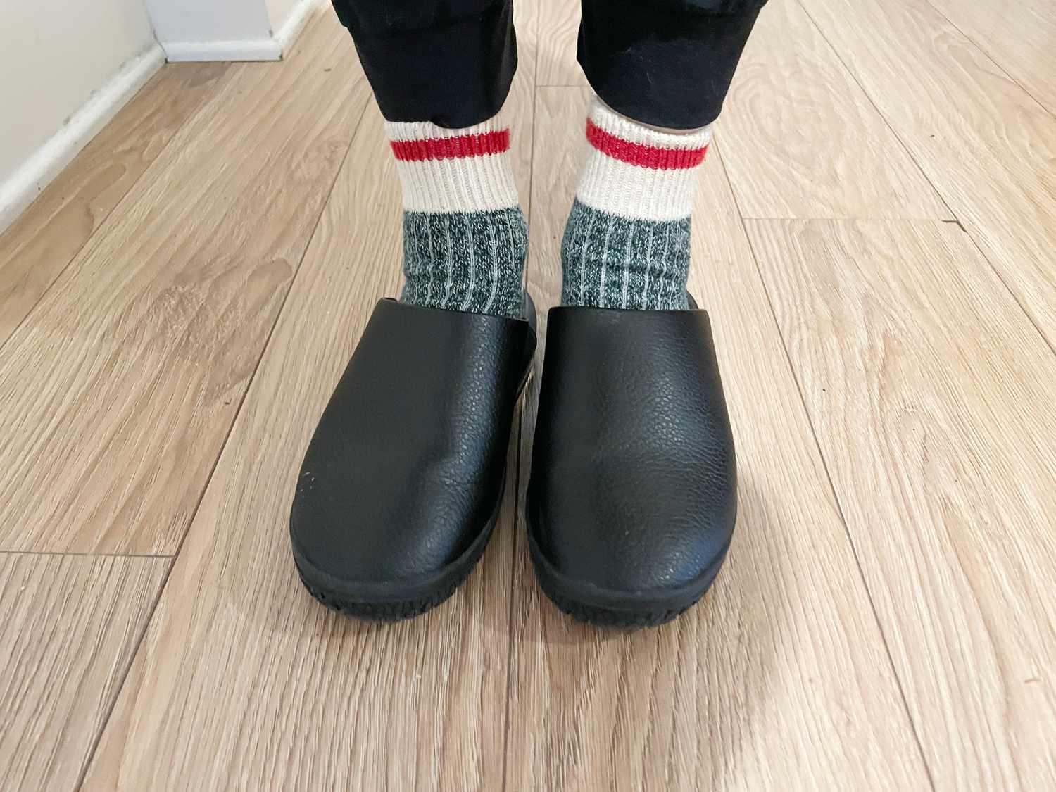 A person wearing a pair of black Snibbs clogs.