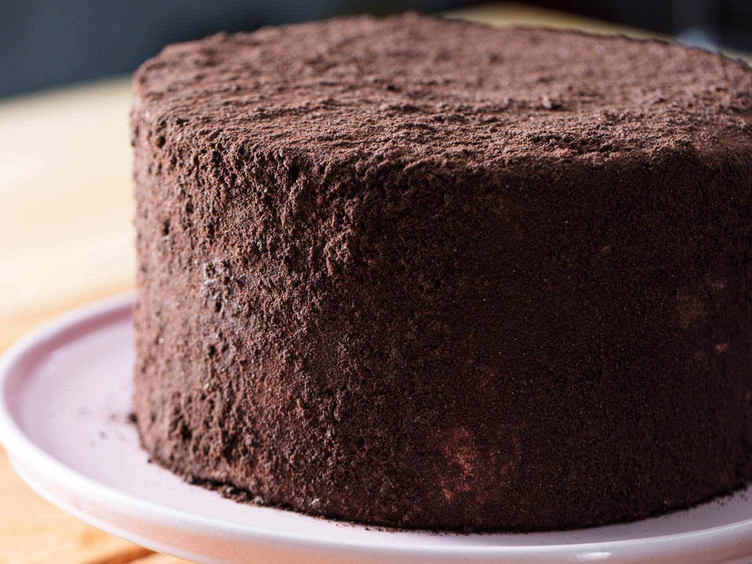 Oreo cookie-crumb coated three-layer Devil's food cake on pink cake stand.