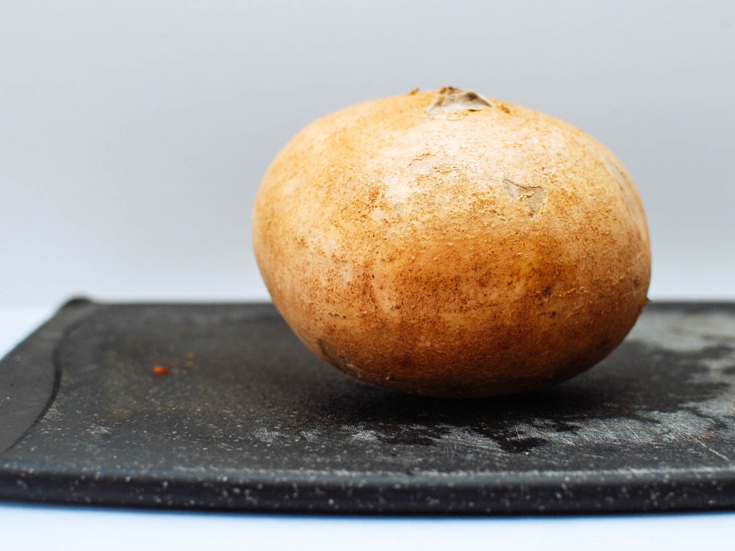 A whole jicama on a black board.