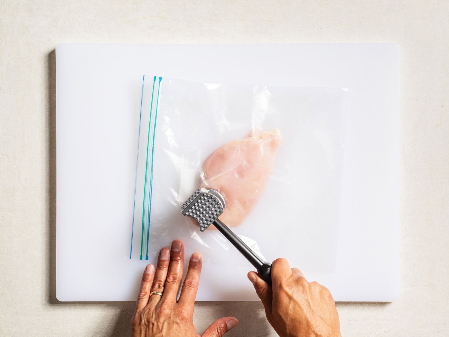 Pounding chicken in a zip-top bag on a cutting board.