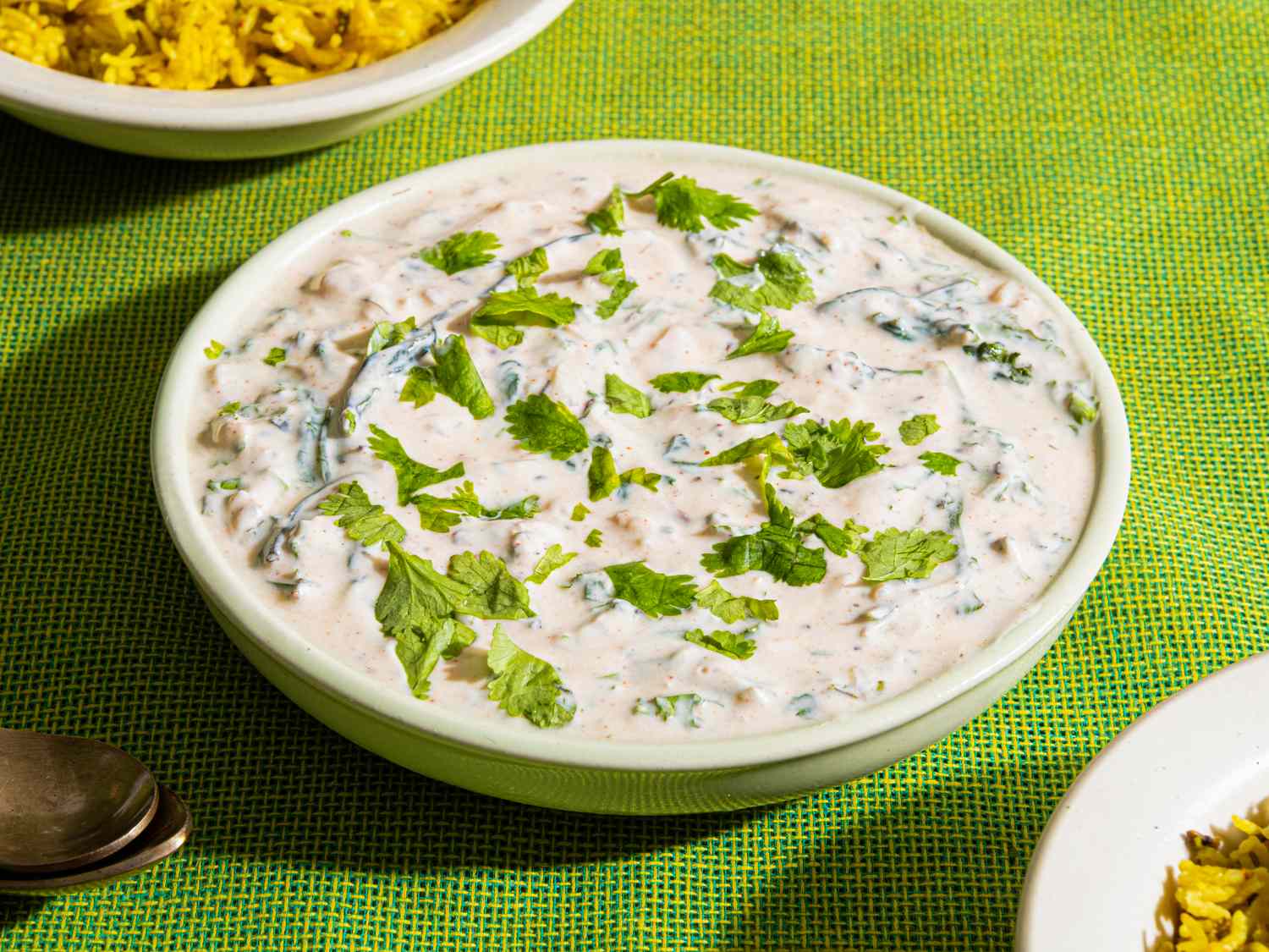 Palak raita in a bowl served on a green surface